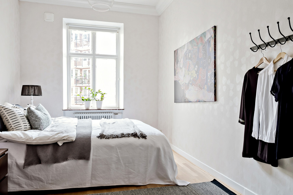 This is an example of a victorian master bedroom in Gothenburg with white walls, light hardwood flooring and beige floors.