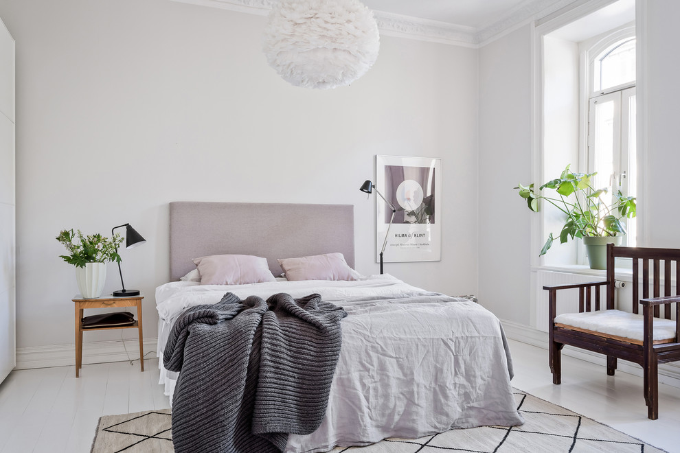 Immagine di una camera da letto nordica con pareti bianche, pavimento in legno verniciato e pavimento bianco