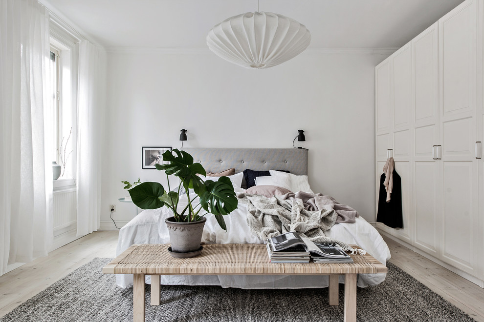 Cette image montre une chambre parentale nordique de taille moyenne avec un mur blanc, parquet clair et un sol beige.