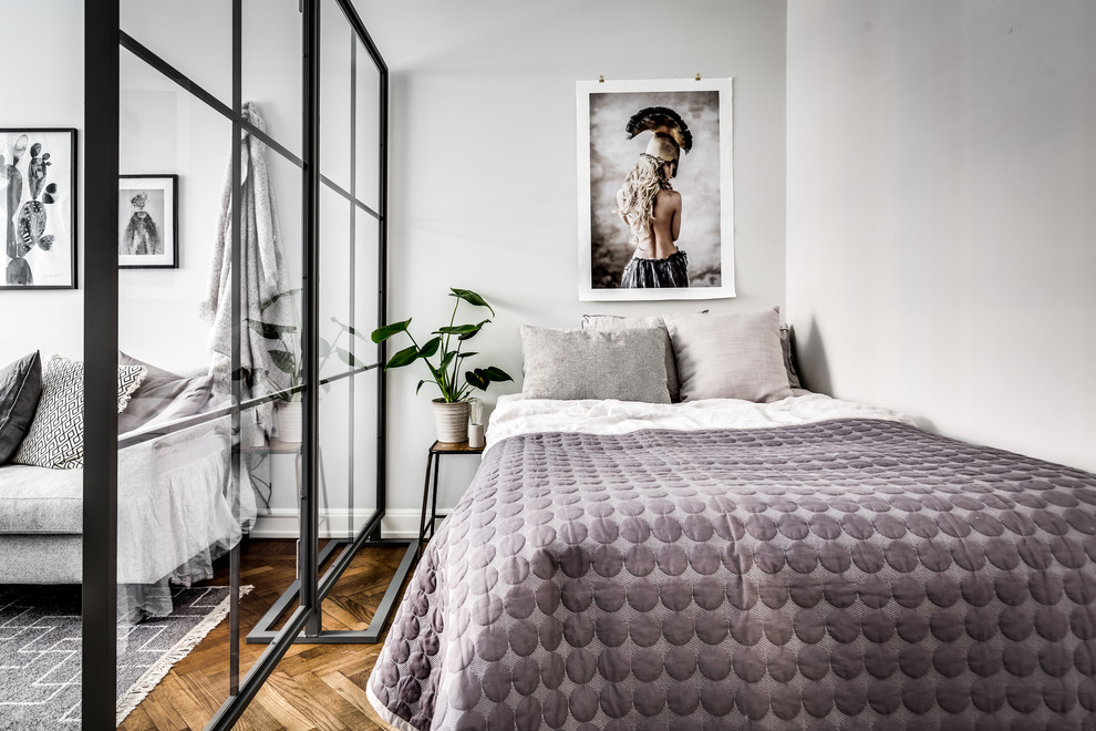 Inspiration for a small scandi master and grey and purple bedroom in Stockholm with white walls, no fireplace, medium hardwood flooring and brown floors.