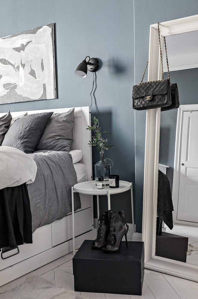 Scandi master bedroom in Stockholm with blue walls, painted wood flooring and white floors.