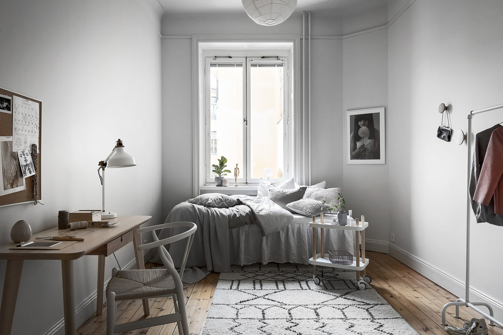 Diseño de habitación de invitados escandinava con paredes blancas, suelo de madera clara, suelo beige y con escritorio