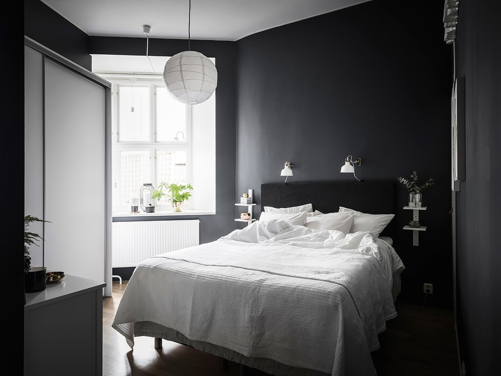 Ejemplo de habitación de invitados gris y negra nórdica pequeña con paredes negras, suelo de madera en tonos medios y suelo marrón