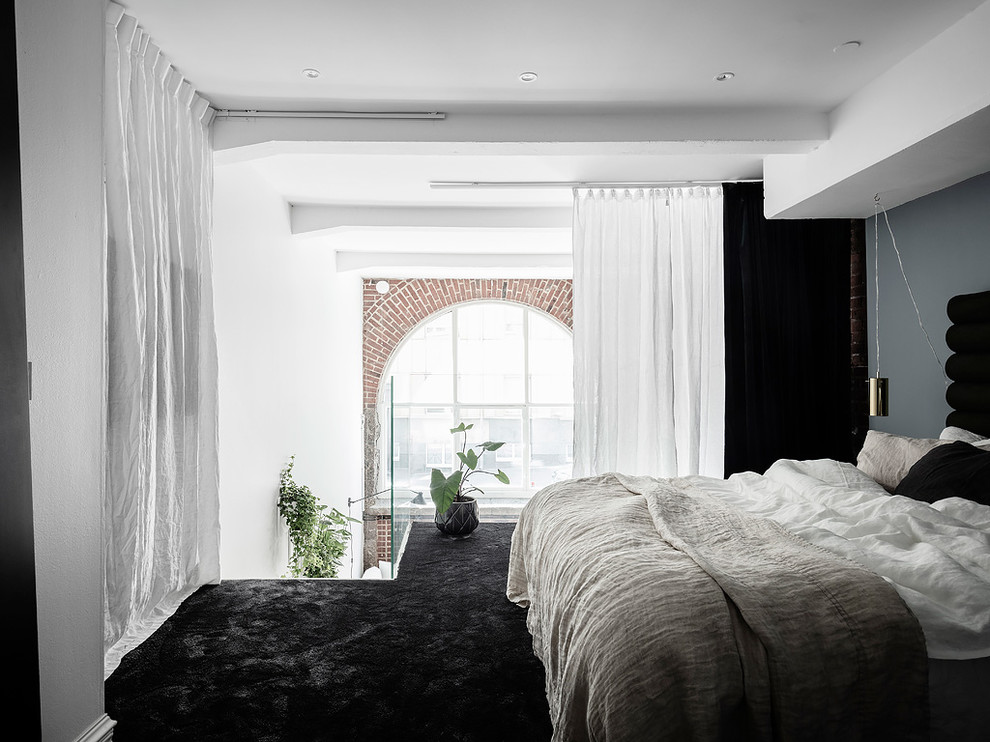 ヨーテボリにある北欧スタイルのおしゃれなロフト寝室 (青い壁、カーペット敷き、黒い床)