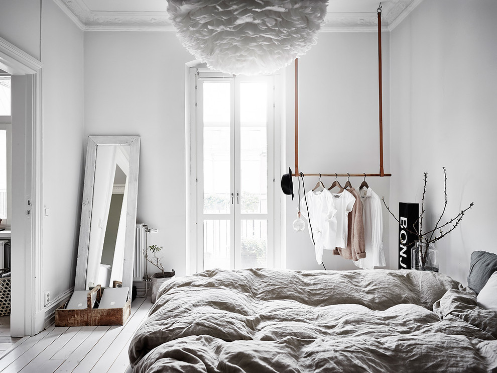На фото: спальня в скандинавском стиле с белыми стенами, деревянным полом и белым полом без камина