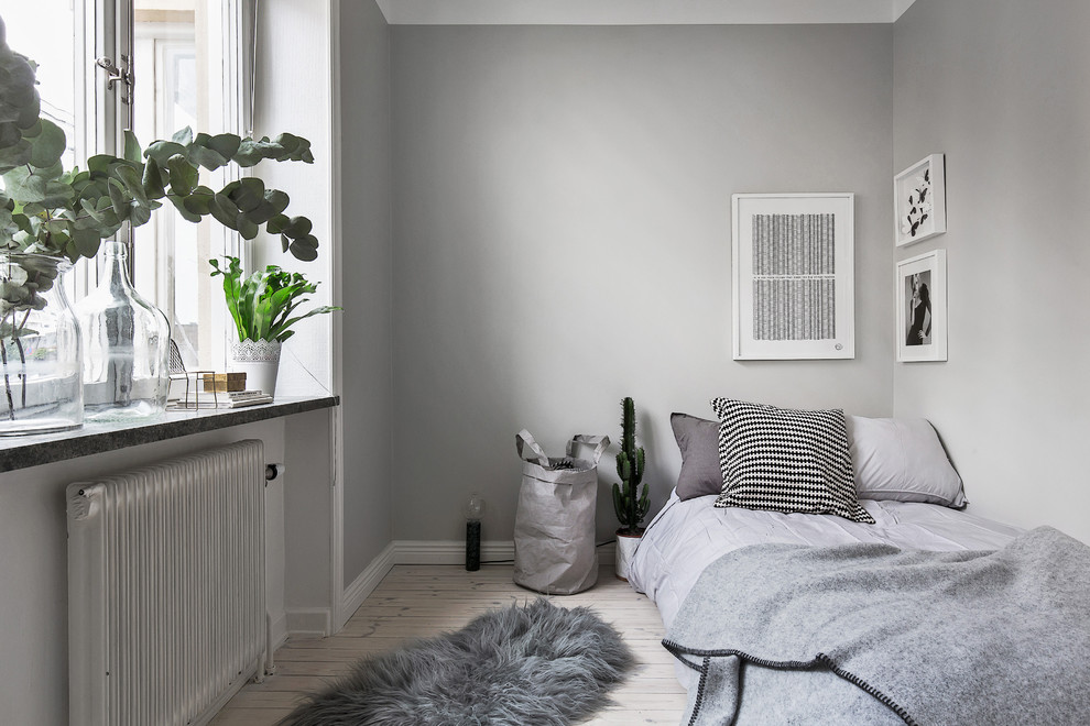 Réalisation d'une petite chambre d'amis nordique avec un mur gris, parquet clair et aucune cheminée.