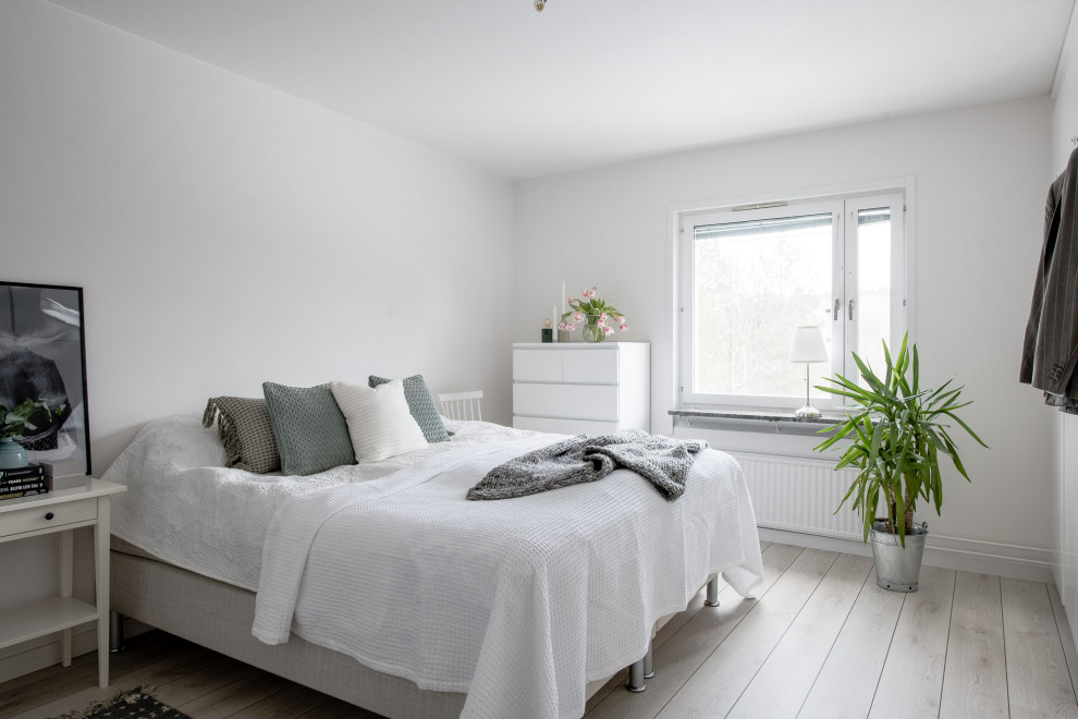 Medium sized scandi bedroom in Stockholm with white walls, light hardwood flooring and beige floors.