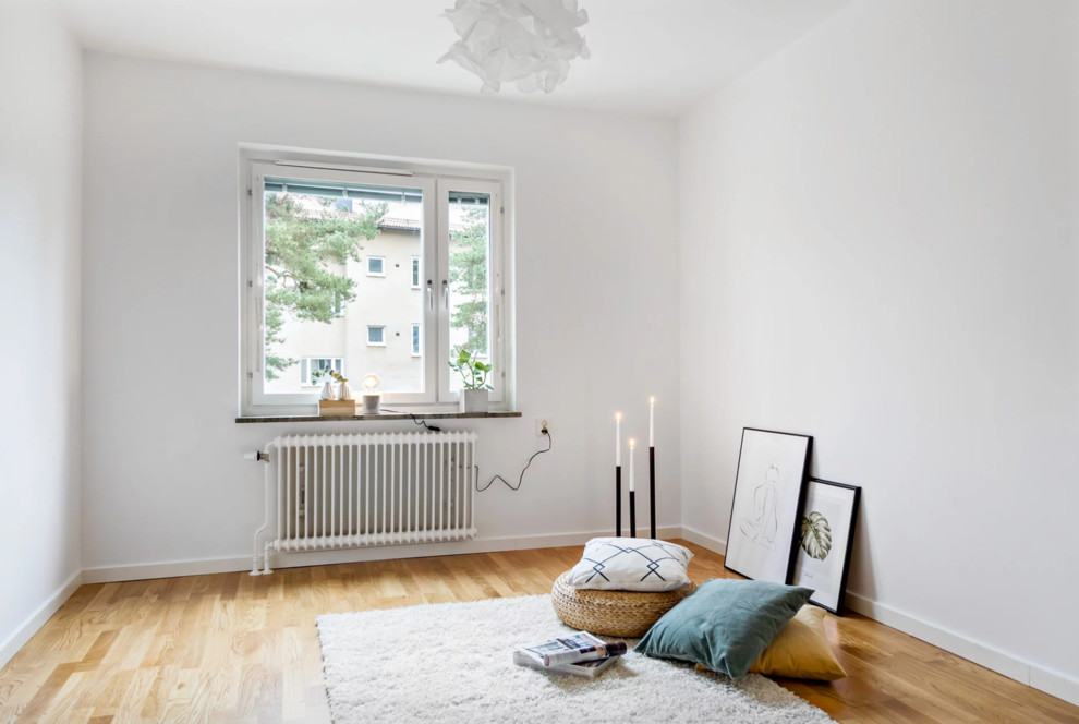 Modelo de dormitorio principal escandinavo de tamaño medio con paredes blancas, suelo de madera clara y suelo beige