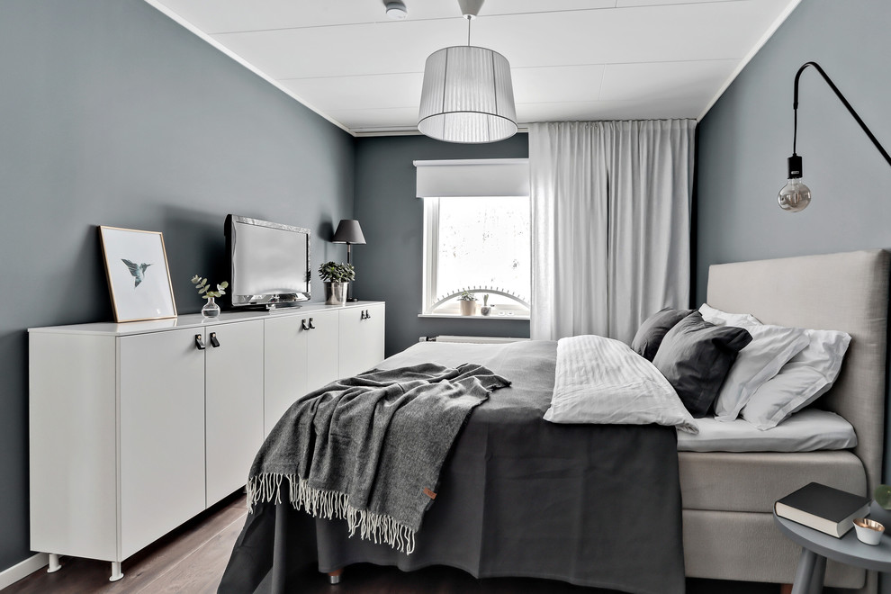 На фото: хозяйская спальня в скандинавском стиле с серыми стенами, полом из ламината, коричневым полом и телевизором без камина