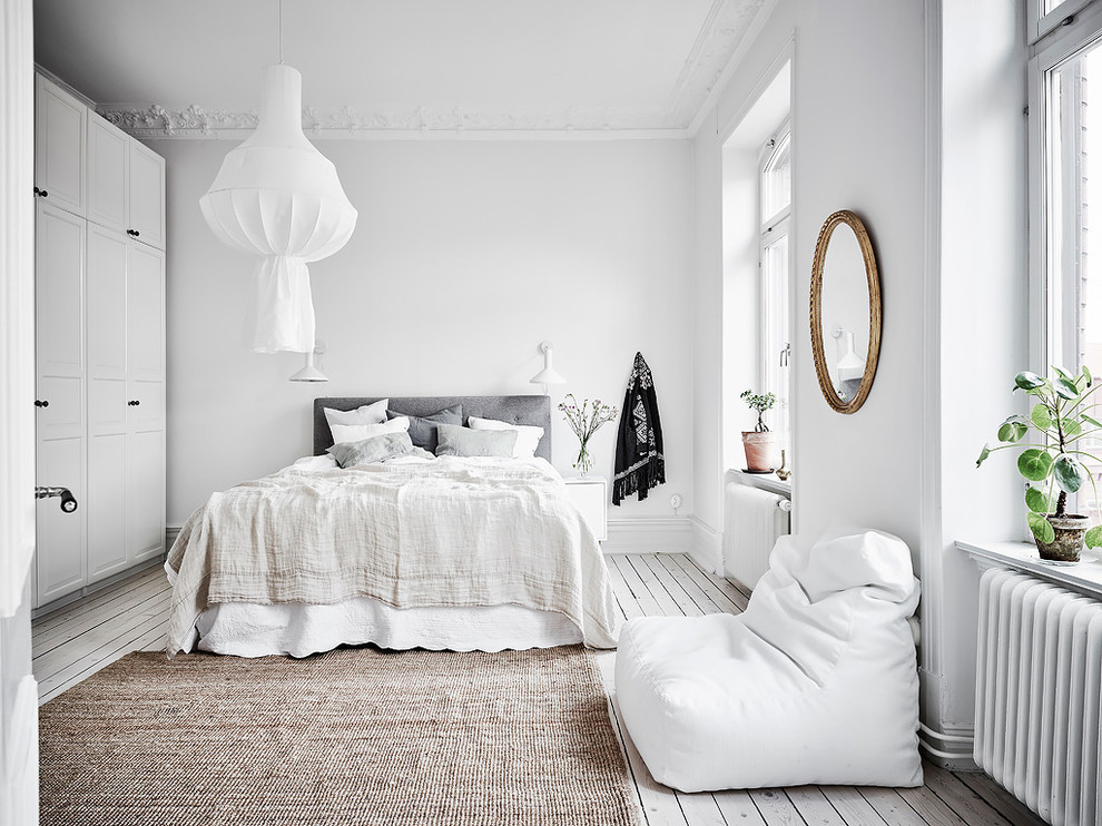 Modelo de dormitorio escandinavo con paredes blancas, suelo de madera pintada y suelo blanco
