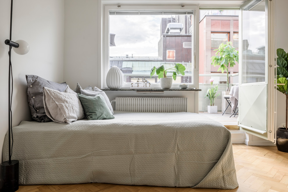 Danish medium tone wood floor and brown floor bedroom photo in Stockholm with white walls