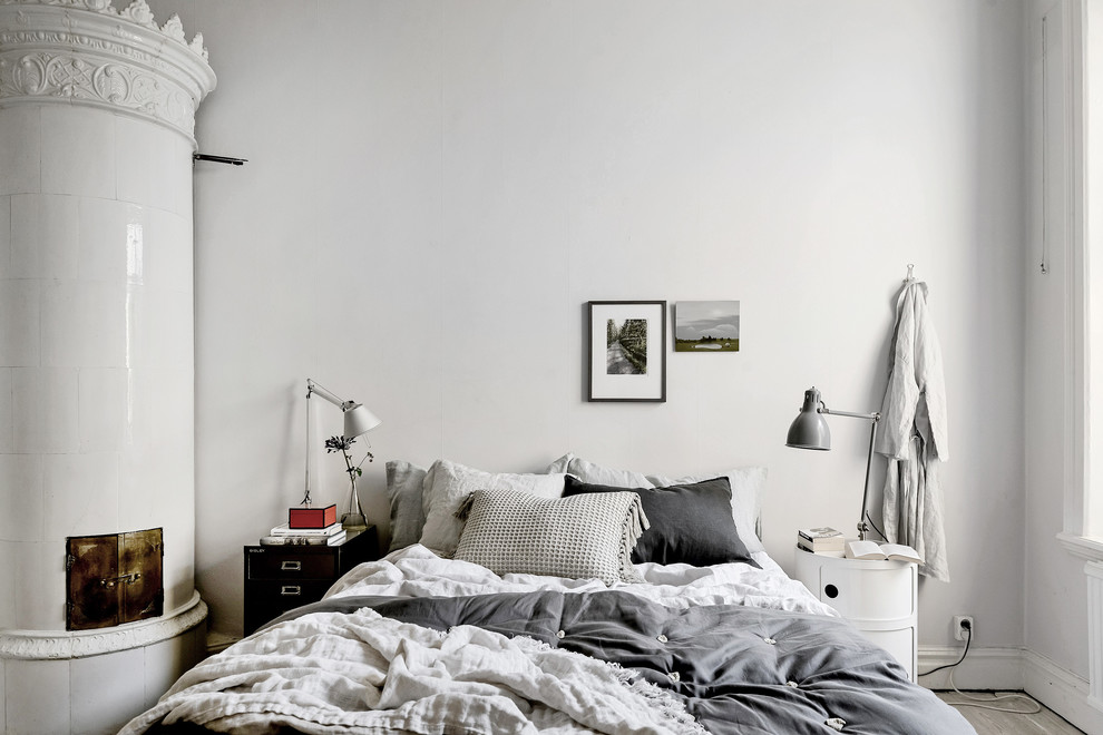 Immagine di una camera matrimoniale scandinava di medie dimensioni con pareti bianche, camino ad angolo, parquet chiaro, cornice del camino piastrellata e pavimento beige