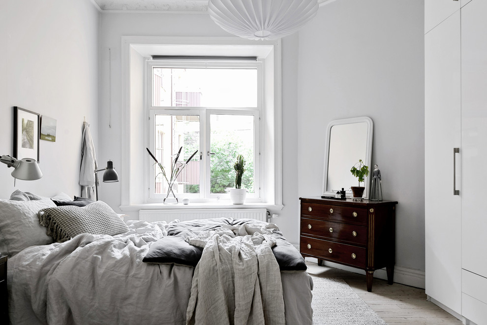 Nordisches Schlafzimmer mit weißer Wandfarbe, hellem Holzboden und beigem Boden in Göteborg