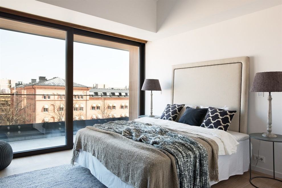 Großes Modernes Hauptschlafzimmer ohne Kamin mit weißer Wandfarbe und hellem Holzboden in Stockholm