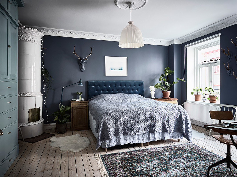 Idee per una camera matrimoniale scandinava con pareti blu, parquet chiaro, stufa a legna, cornice del camino in metallo e pavimento beige