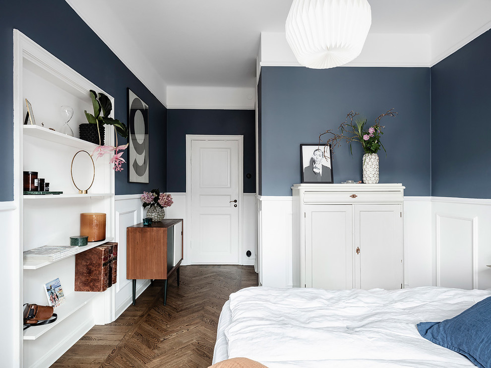 Inredning av ett klassiskt mellanstort sovrum, med blå väggar, mörkt trägolv och brunt golv