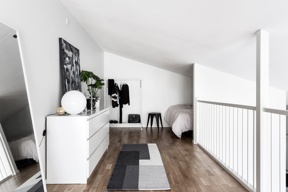 Skandinavisches Schlafzimmer im Dachboden mit weißer Wandfarbe, braunem Holzboden und braunem Boden in Stockholm