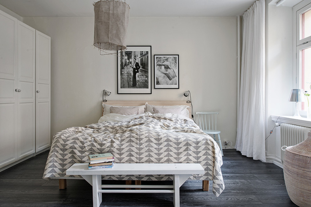 Large scandi master bedroom in Gothenburg with white walls, dark hardwood flooring and no fireplace.