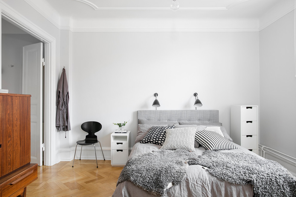 Стильный дизайн: спальня в скандинавском стиле с белыми стенами и паркетным полом среднего тона - последний тренд