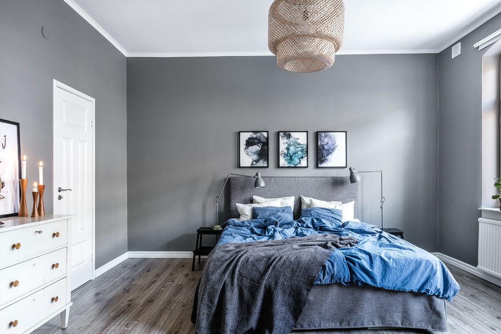 Diseño de dormitorio principal nórdico de tamaño medio con paredes grises, suelo de madera en tonos medios y suelo gris