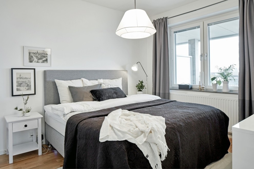 Großes Skandinavisches Hauptschlafzimmer ohne Kamin mit weißer Wandfarbe und hellem Holzboden in Göteborg