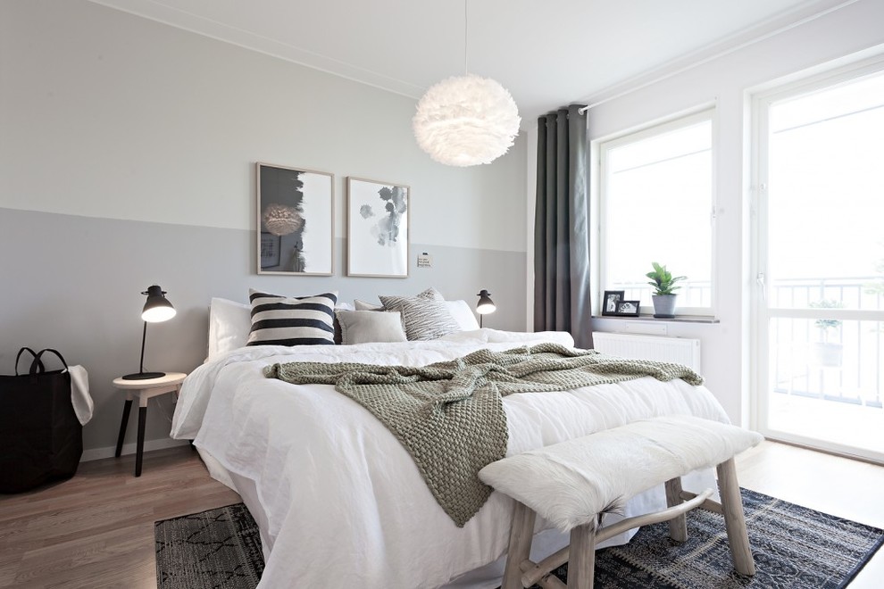 На фото: большая хозяйская спальня: освещение в скандинавском стиле с белыми стенами и паркетным полом среднего тона