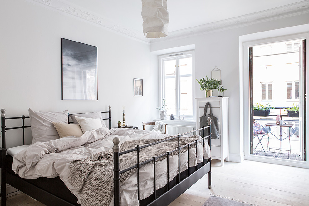 Foto de dormitorio principal nórdico de tamaño medio sin chimenea con paredes blancas y suelo de madera clara