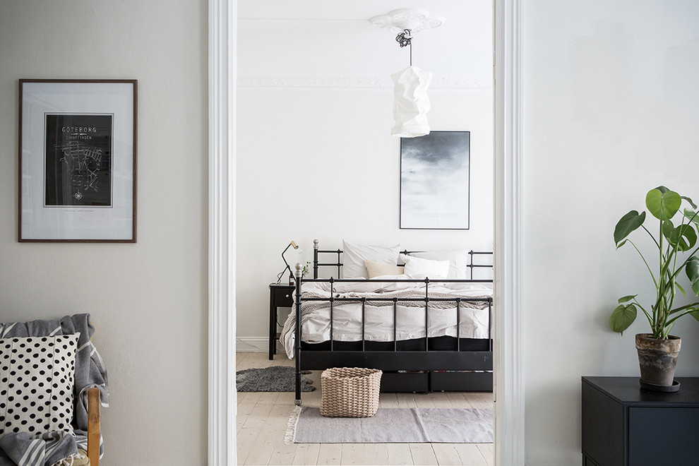 This is an example of a scandi bedroom in Gothenburg with white walls and light hardwood flooring.