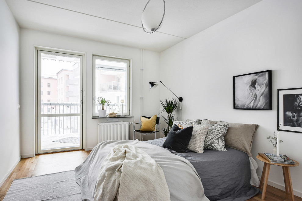 Idéer för att renovera ett minimalistiskt sovrum, med vita väggar, ljust trägolv och brunt golv