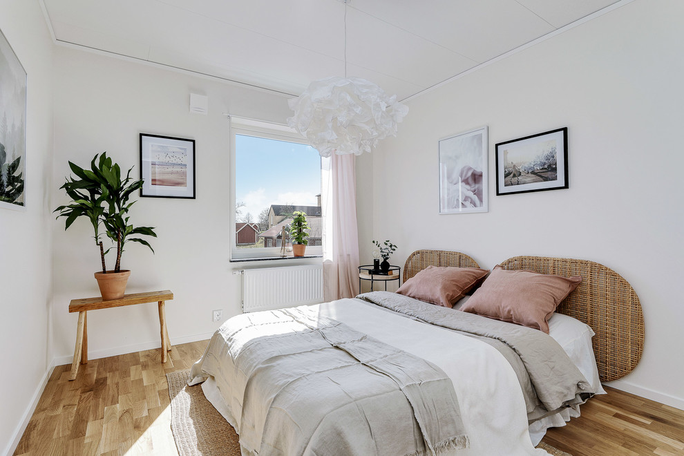 Exemple d'une chambre parentale scandinave de taille moyenne avec un mur blanc, un sol en bois brun et un sol beige.