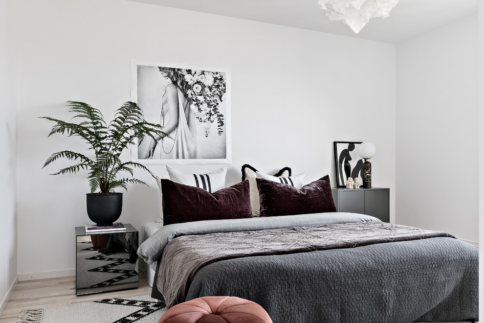 Scandi bedroom in Stockholm with white walls, light hardwood flooring and beige floors.