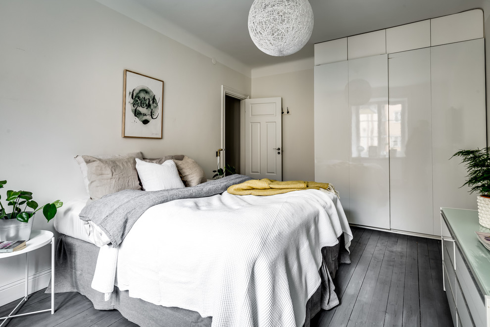 This is an example of a medium sized scandi bedroom in Stockholm with white walls, dark hardwood flooring and grey floors.