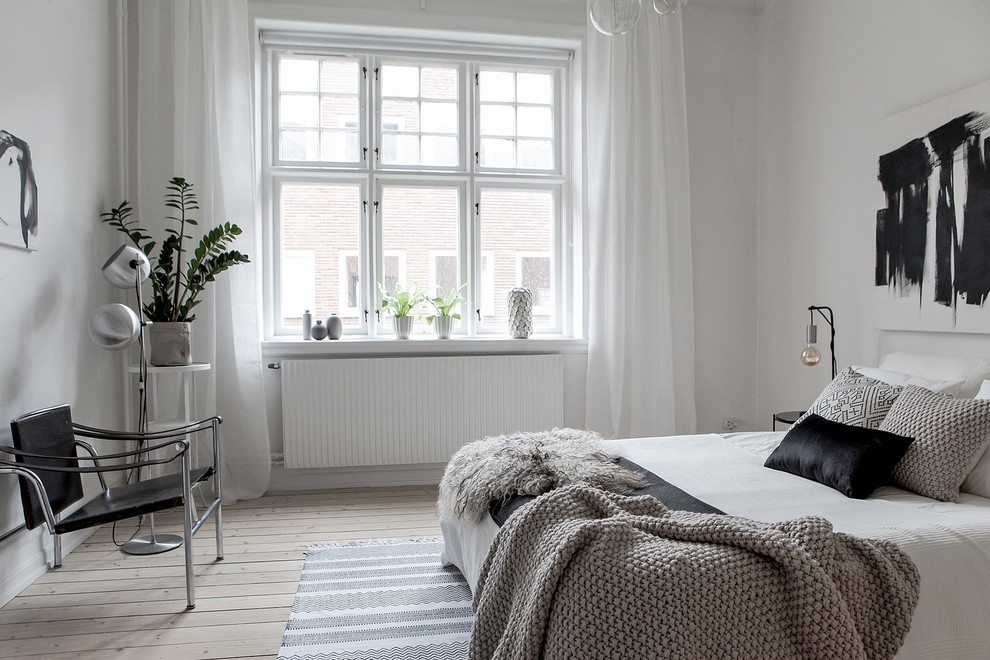 Design ideas for a large scandi bedroom in Malmo with white walls, light hardwood flooring and beige floors.