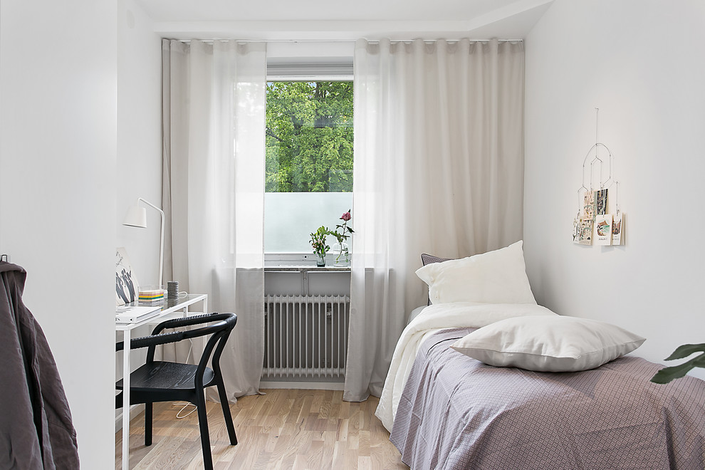 Immagine di una camera degli ospiti nordica di medie dimensioni con pareti bianche, pavimento in legno massello medio e nessun camino