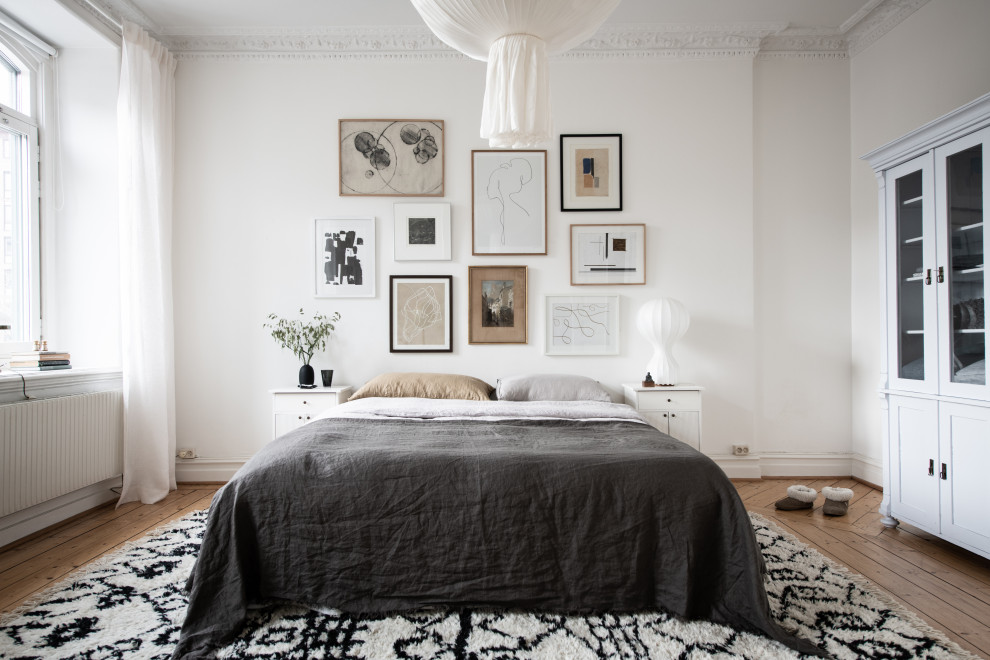 Nordisches Schlafzimmer ohne Kamin mit weißer Wandfarbe und hellem Holzboden in Göteborg