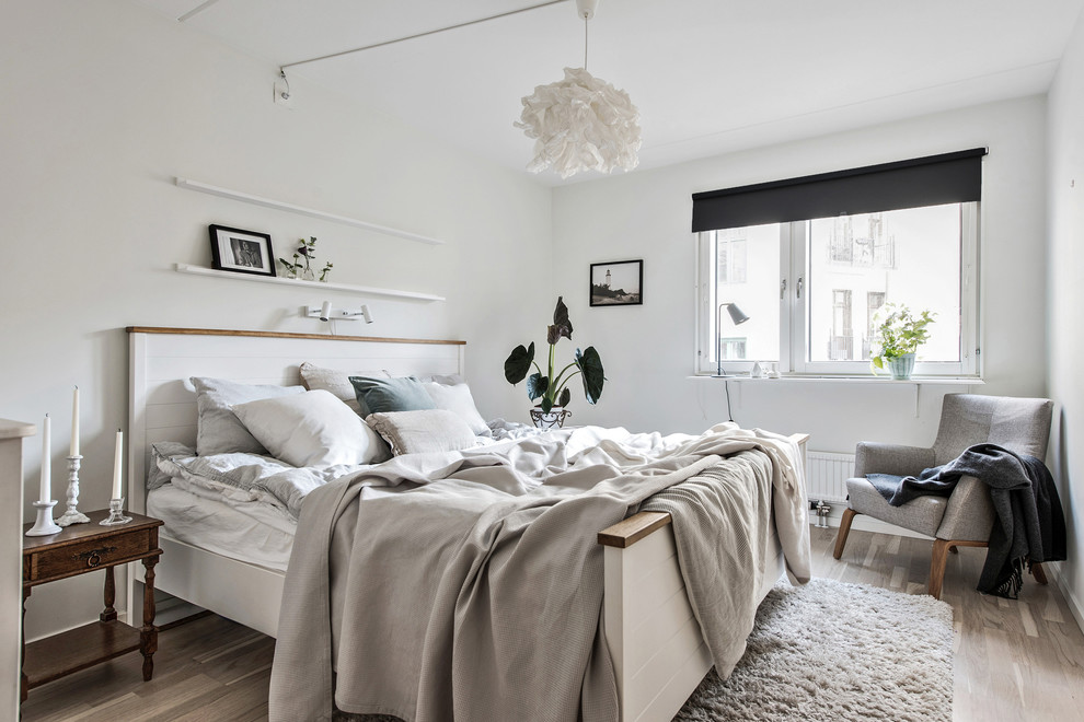 Foto de dormitorio nórdico con paredes blancas, suelo de madera clara y suelo beige