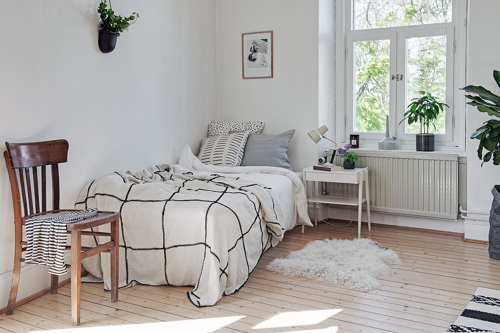 Пример оригинального дизайна: гостевая спальня (комната для гостей), среднего размера в скандинавском стиле с белыми стенами, светлым паркетным полом и кроватью в нише без камина