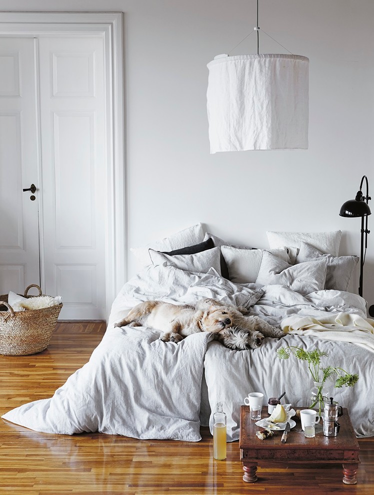 Großes Nordisches Hauptschlafzimmer ohne Kamin mit weißer Wandfarbe und braunem Holzboden in Stockholm