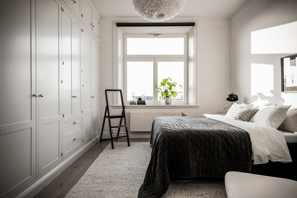 Aménagement d'une chambre scandinave avec un mur blanc, un sol en bois brun et un sol gris.