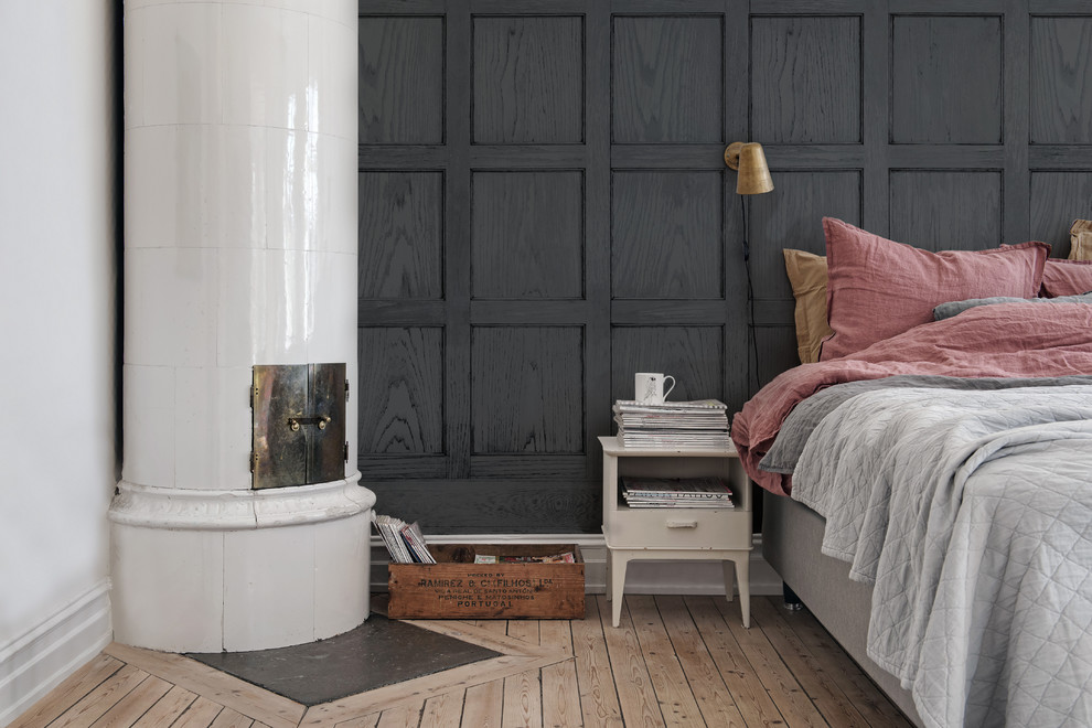 Mittelgroßes Modernes Hauptschlafzimmer mit Eckkamin, schwarzer Wandfarbe und hellem Holzboden in Göteborg