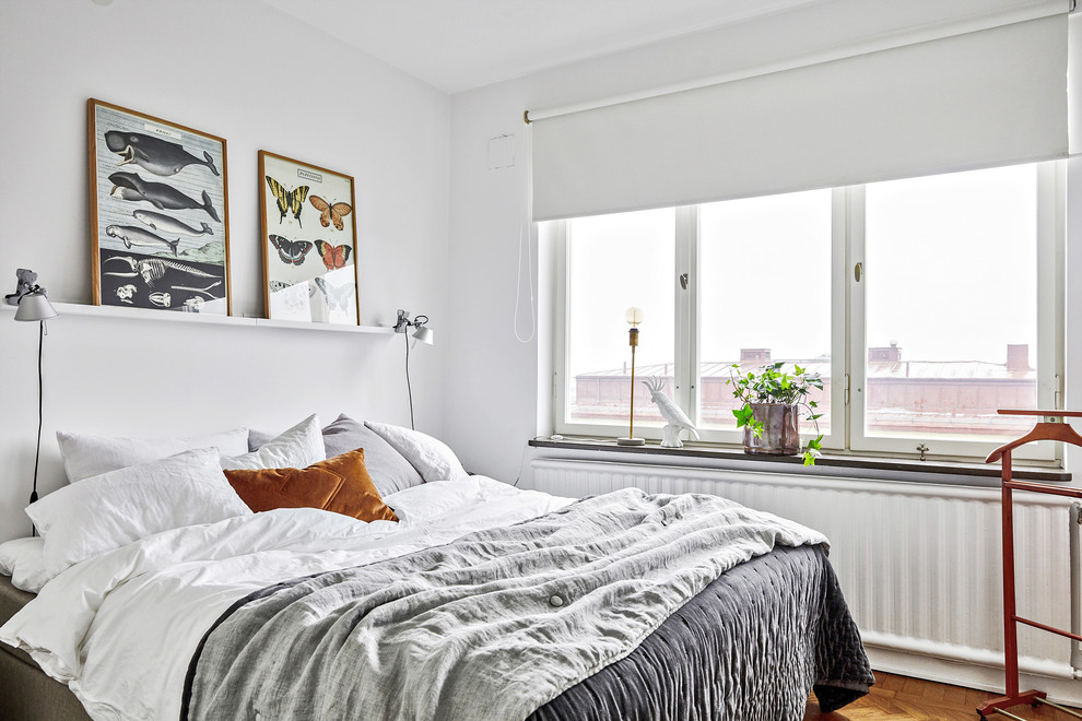 На фото: маленькая хозяйская спальня в скандинавском стиле с белыми стенами, паркетным полом среднего тона и коричневым полом для на участке и в саду с
