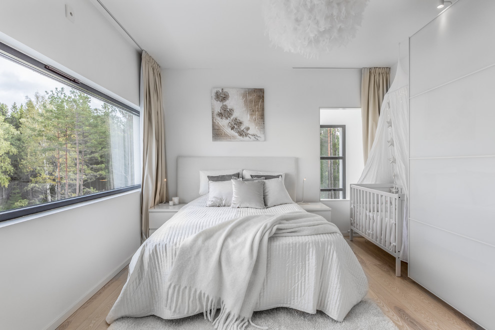 Modelo de dormitorio escandinavo de tamaño medio sin chimenea con paredes blancas, suelo de madera clara y suelo beige