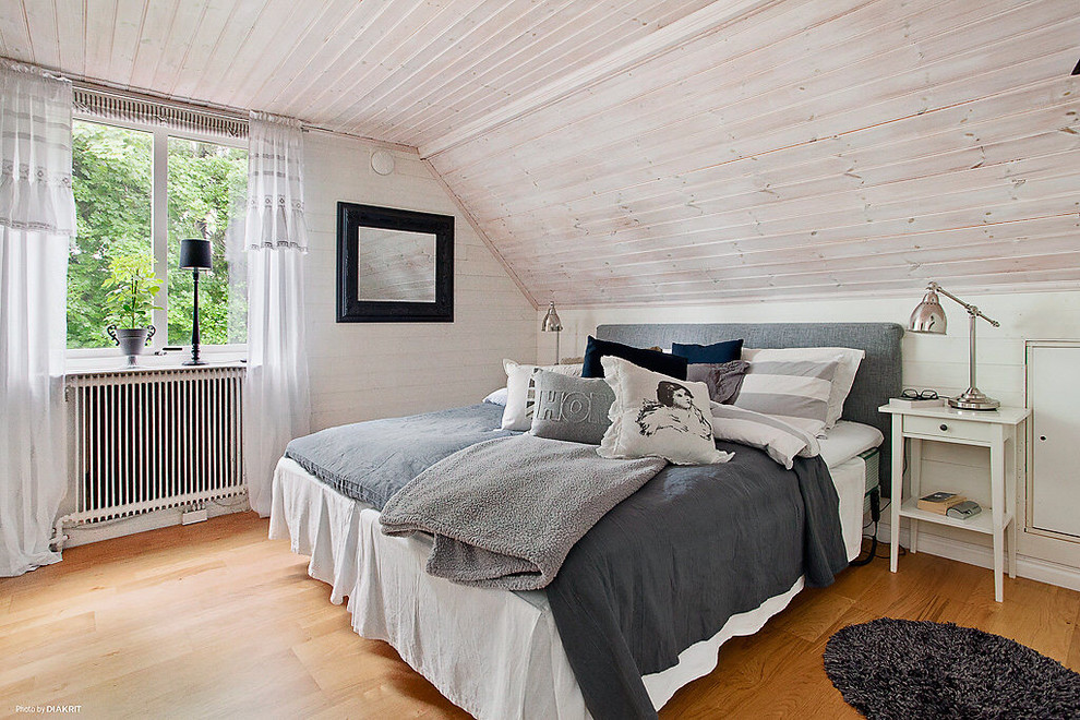 Cette image montre une chambre parentale traditionnelle de taille moyenne avec un mur blanc, un sol en bois brun et aucune cheminée.