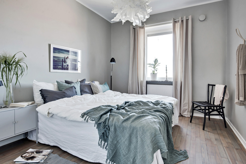 Idéer för minimalistiska sovrum, med grå väggar, mellanmörkt trägolv och brunt golv