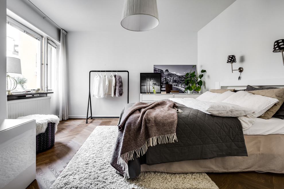 This is an example of a scandi master bedroom in Stockholm with white walls, dark hardwood flooring and brown floors.