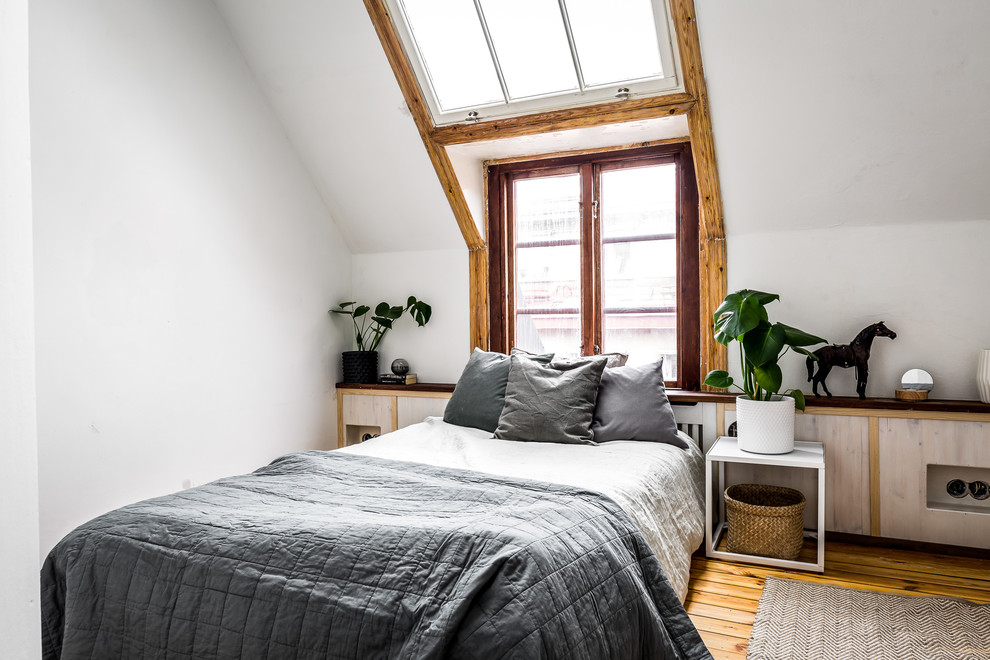Imagen de dormitorio principal nórdico con suelo de madera en tonos medios, paredes blancas y suelo marrón