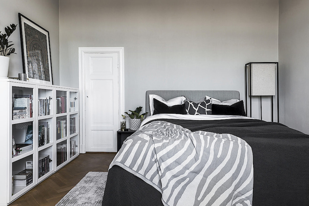 This is an example of a scandi master bedroom in Stockholm with grey walls, dark hardwood flooring and brown floors.