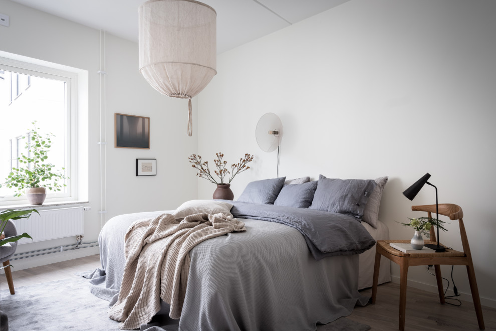 Idéer för ett nordiskt sovrum, med vita väggar, ljust trägolv och beiget golv