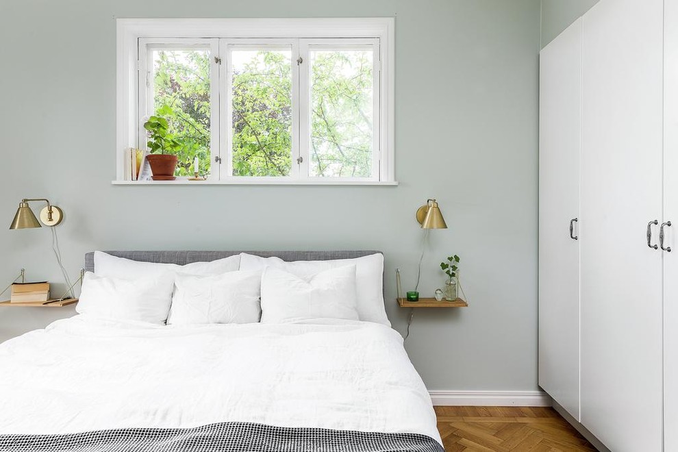 Immagine di una camera da letto nordica con pareti verdi e pavimento in legno massello medio