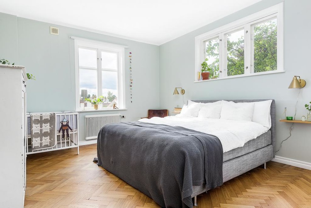 Bild på ett minimalistiskt sovrum, med gröna väggar och mellanmörkt trägolv